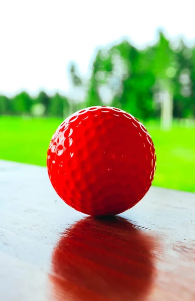 Rode Golfbal Een Houten Oppervlak Groene Veld Blauwe Hemel Macro — Stockfoto