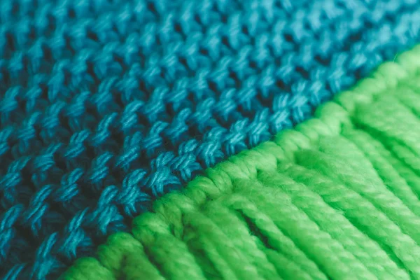 Knitwear woolen textile texture backdrop, macro. Blue and green color palette clothes, scarf tassels.