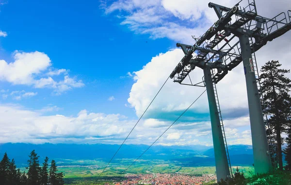 Steel cable way tower construction, blue sky on the background. Vertical photo depicts mountain rope way transportation part for ski and snowboarding resort. Europe, Balkan mountains, Bansko city.