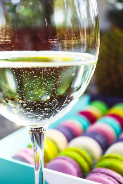 Champagne glass and a box of assorted macaroons sweets, close up, backdrop. Female party concept.
