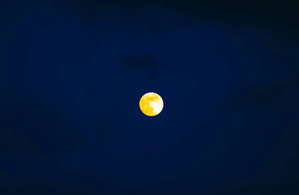 A scary yellow fool moon of a dark sky with clouds, mystical night background.