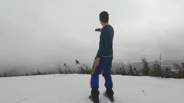 Мандрівник фотографує гори в тумані — стокове відео