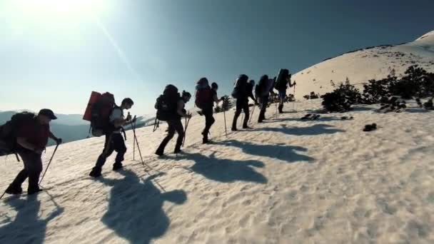 Група туристів подорожує по засніжених горах — стокове відео