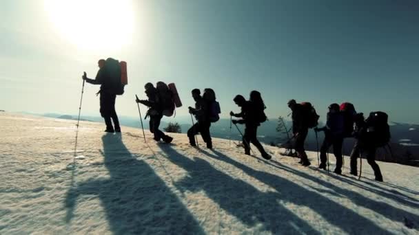 Um grupo de turistas viaja pelas montanhas cobertas de neve — Vídeo de Stock