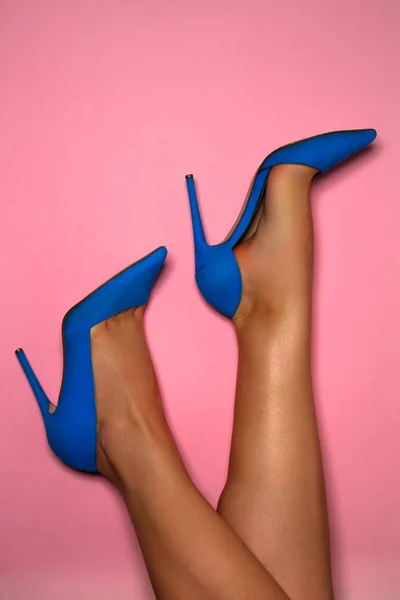 创意照片一个美丽的时尚时尚现代对高跟鞋妇女蓝色绒面鞋在工作室在粉红色背景的妇女腿 — 图库照片