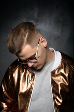 Gri bir arka plan üzerinde modern moda moda giysiler içinde stüdyoda poz genç bir erkek erkek model moda fotoğraf portresi