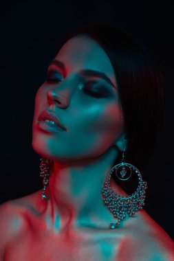 Koyu siyah bir arka plan üzerinde stüdyoda trendy modern jel ışık genç bir güzel çekici kız modeli Moda trendy portre fotoğrafı