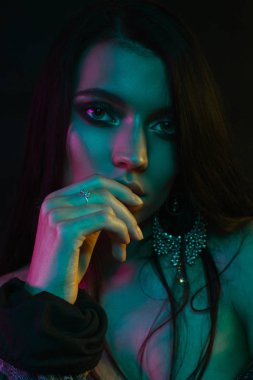 Koyu siyah bir arka plan üzerinde stüdyoda trendy modern jel ışık genç bir güzel çekici kız modeli Moda trendy portre fotoğrafı