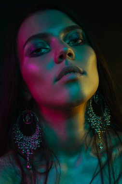 Koyu siyah bir arka plan üzerinde stüdyoda trendy modern jel ışık genç bir güzel çekici kız modeli Moda trendy portre fotoğrafı