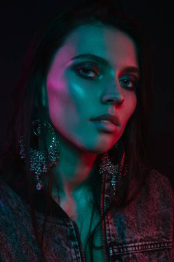 Koyu siyah bir arka plan üzerinde stüdyoda trendy modern jel ışık genç bir güzel çekici kız modeli Moda trendy portre fotoğrafı
