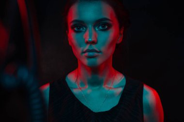 Koyu siyah bir arka plan üzerinde stüdyoda trendy modern jel ışık genç bir güzel çekici kız modeli Moda trendy portre fotoğrafı