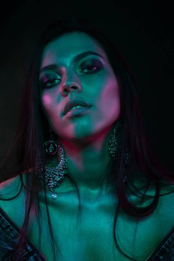 Koyu siyah bir arka plan üzerinde stüdyoda trendy modern jel ışık genç bir güzel çekici kız modeli Moda trendy portre fotoğrafı