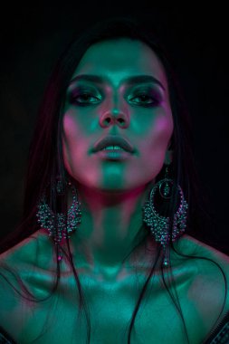 Koyu siyah bir arka plan üzerinde stüdyoda trendy modern jel ışık genç bir güzel çekici kız modeli Moda trendy portre fotoğrafı