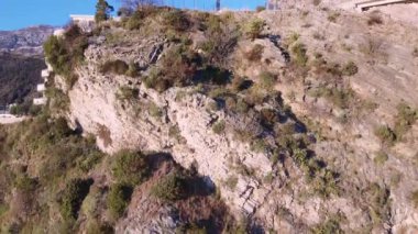 İHA 'dan ateş ediliyor. Dağlarla çevrili, yeşil ormanlarla kaplı beyaz tatil köyünün üzerinde yavaşça yükseliyor. Açık mavi gökyüzü, Karadağ 'ın çarpıcı panoramik manzarası.