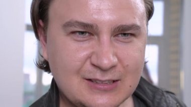Genç adam öfkeyle homurdanıyor ve yüz yüze geliyor ve siyah el izi bırakıyor, kapat. Film veya tiyatro performansı için oyunculuk makyajı uygulanıyor.