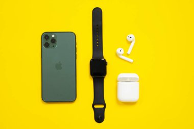 5 Haziran 2020, Rostov, Rusya: Cep telefonu iPhone 11 gece yarısı yeşil renkli Pro, kablosuz kulaklık açık çanta ve Apple Watch S4 sarı arka plan, üst görünüm, kopyalama alanı