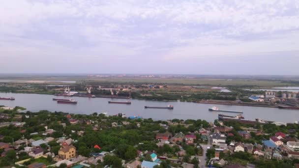 Vista aérea a partir do helicóptero em u bela paisagem com rio, navios, guindastes na costa distante, e campos intermináveis para o horizonte. Bom tempo, primavera ou verão. Ao ar livre . — Vídeo de Stock