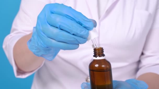 Hands in protective gloves collect a transparent preparation using a pipette from a dark glass bottle. Person in a white coat, a laboratory assistant conducting a study or a medical professional. — Stock Video