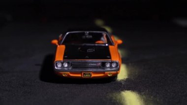 14 Temmuz 2020, Rostov, Rusya: Kamera soldan sağa hareket ederek 1970 model havalı turuncu oyuncak araba Dodge Challenger 'ın yola çıkışını gösteriyor. Koleksiyonluk modellerin muhteşem sergisi.