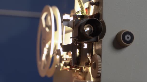 Film d'epoca proiettore con bobine funziona e mostrando film, lampadina è luminoso all'interno attraverso lente. Vecchie attrezzature surriscalda e fuma a causa di sovraccarico, riparazioni e manutenzione sono necessari. — Video Stock
