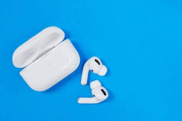 Rostov, Russia - July 06, 2020: Wireless headphones Apple AirPods Pro in opened charging case with active noise cancellation immersive sound, on blue background, copy space. — Stock Photo, Image