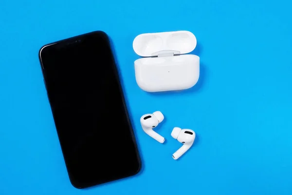 Rostov, Rusya - Temmuz 06, 2020: Smartphone Apple iPhone 11 Pro ve kablosuz kulaklıklar mavi arka plan, üst görünüm, kopyalama alanı aktif yaşam tarzı için açık şarj kutusu.