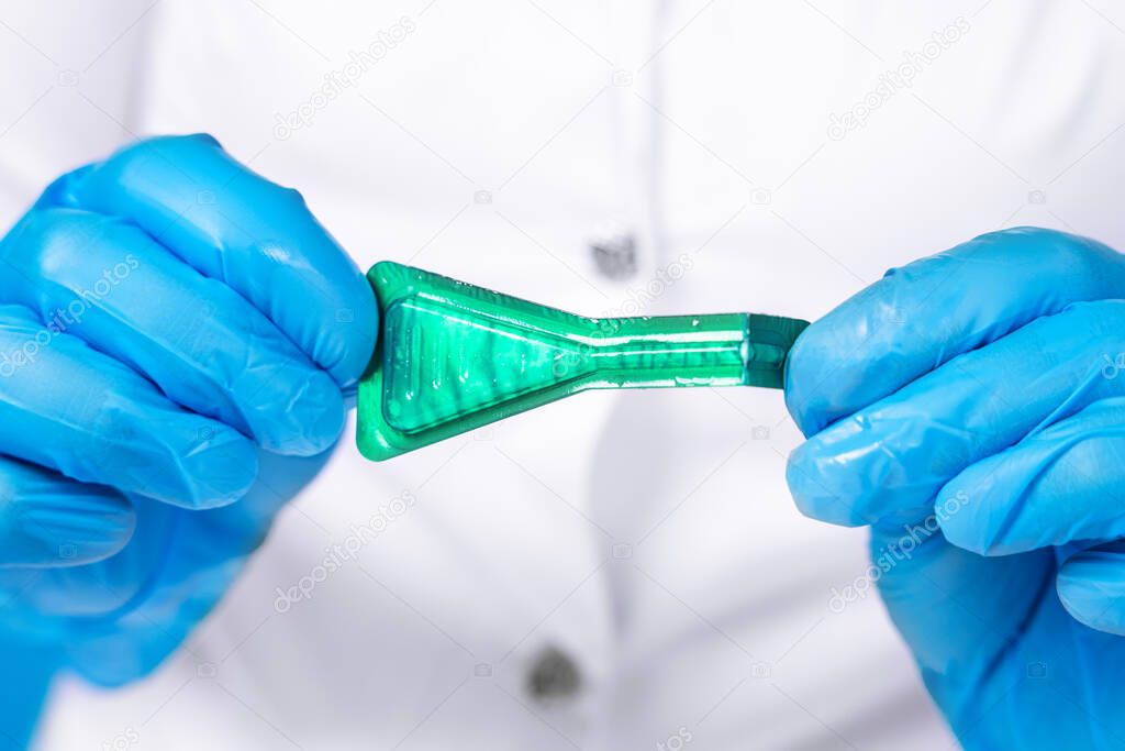 Doctor in medical coat and sterile protective silicone gloves open bottle of medication according to prescription with pipette against ticks, fleas and other parasites to the dogs withers.