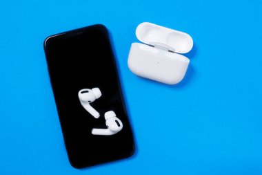 Rostov, Rusya - Temmuz 06, 2020: Smartphone Apple iPhone 11 Pro ve kablosuz kulaklıklar mavi arka plan, üst görünüm, kopyalama alanı aktif yaşam tarzı için açık şarj kutusu.