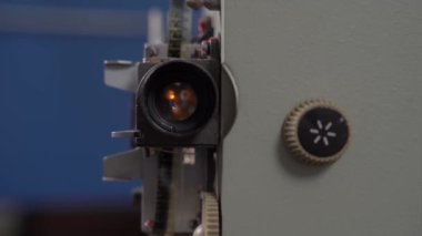 Cihazın içinde ampul yanıyor ve film projektörünün merceğiyle parlıyor, ön görüş, kapat. İstenen modu ayarlamak için kolu çeviren kişi. Eski ekipmanların yapılandırılması ve bakımı.