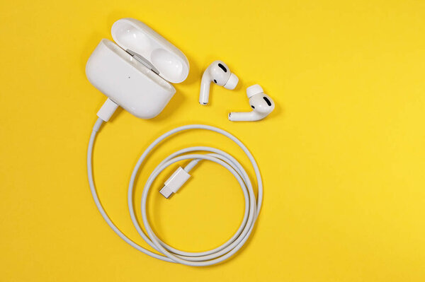 Ростов, Россия - 06 июля 2020 года: Беспроводные наушники Apple AirPods Pro с мягкими, гибкими силиконовыми коническими наконечниками, соответствующими форме человеческого уха в корпусе зарядки, подключенном к шнуру, вид сверху, пространство для копирования