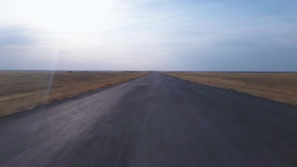 Drone footage flying over deserted road in the middle of harvested agricultural fields, rapidly gaining speed and altitude. Travel through abandoned wild territories. Plane taking off on the runway — Stock Video