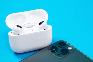 Rostov, Rusya - Temmuz 06, 2020: Smartphone Apple iPhone 11 Pro of Midnight Green color ve kablosuz kulaklıklar mavi arkaplan, üst görünüm, kopyalama alanı.
