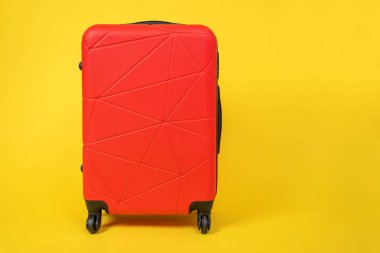 Seyahat için tekerlekli kırmızı rahat bavul sarı arka plan, ön görüş, reklam metni için kopyalama alanı. Tatil ya da iş seyahati bagaj konsepti