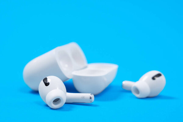 Ростов, Россия - 06 июля 2020 года: Беспроводные наушники Apple AirPods Pro в открытом корпусе зарядки с активным шумоподавлением иммерсивного звука, на синем фоне, место для копирования