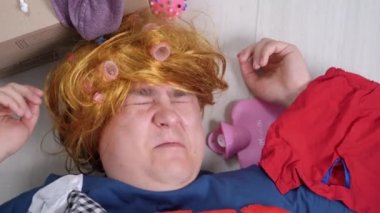Pembe bigudileri olan eski püskü peruklu deli adam yerde dağınık şeyler ve ısıtma yastığıyla yatıyor. İşleri yoluna koymaya çalışıyor, küçük bir dairede depolama yapıyor. Toplama ile ilgili psikolojik sorunlar