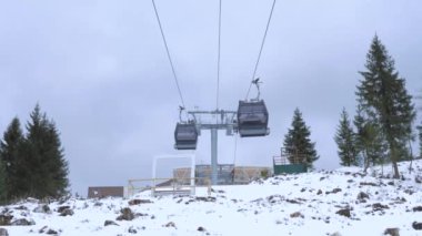 Dağ kablosunun örtülü kamaraları karlı yamaçlarda yukarı ve aşağı gider, kozalaklı ağaçlar etrafını sarar, aşağıyı görür. Tatil ya da tatillerde kayak merkezinde aktif dinlenme