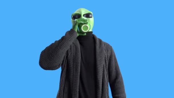 Alien em um cardigan preto elegante anda ao redor da nave espacial com uma caneca de bebida quente, caminha e olha em volta, bebe café. Chromakey. Rotina matinal — Vídeo de Stock