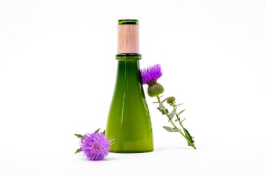 Beyaz arka planda doğal vegan dostu kozmetik ürünlerle dolu ahşap kapaklı yeşil cam şişe, yakın çevrede taze burdock çiçeği, reklam için kopyalama alanı