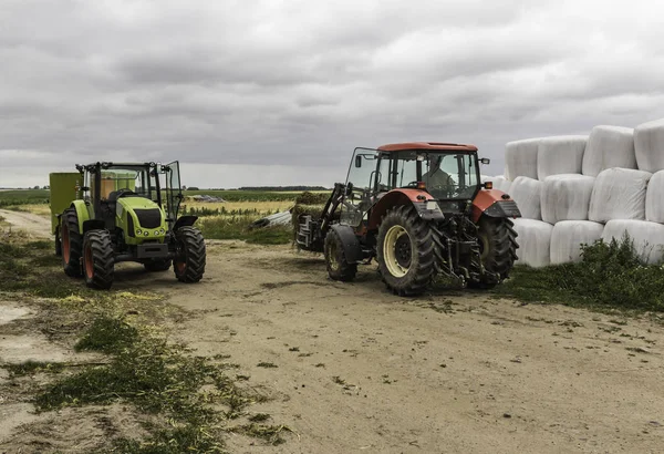 農業機械および装置 ローダー付けトラクターは 牛用混合飼料のディストリビューターのサイレージのベールを読み込みます ポーランドのポドラシェ県 — ストック写真