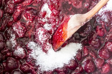 Kiraz reçeli pişirme. Bir tahta kaşıkla karıştırın sıcak koyu kırmızı kiraz ve beyaz şeker. Meyve, meyveler, yiyecek, mutfak ve pişirme hakkında bir sitedir.