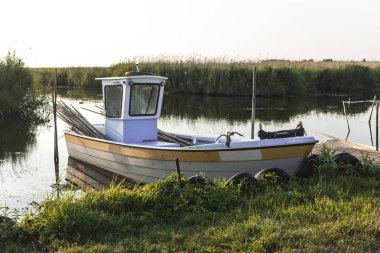 Vistula Bay erken sabahı. Bir balıkçı teknesi küçük bir ahşap İskeleye demirlemiş. Sazlık ve sessiz su. Doğa, deniz, Balık tutma, sanat, arka plan hakkında site.