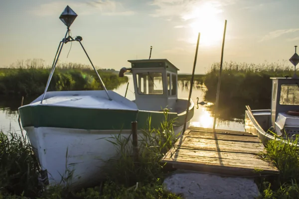 Early morning on the Vistula Bay. A fishing boat moored to a small wooden pier.Reeds and quiet water. Site about nature,sea, fishing, art, background.