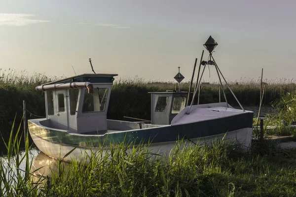 Early morning on the Vistula Bay. A fishing boat moored to a small wooden pier.Reeds and quiet water. Site about nature,sea, fishing, art, background.