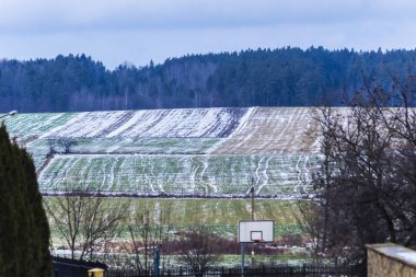 Köyün sokakta. Biraz yeşil çayırlar ve sürülmüş alanlar günü kar 's. Orman içinde belgili tanımlık geçmiş. Kış başında Avrupa'da.