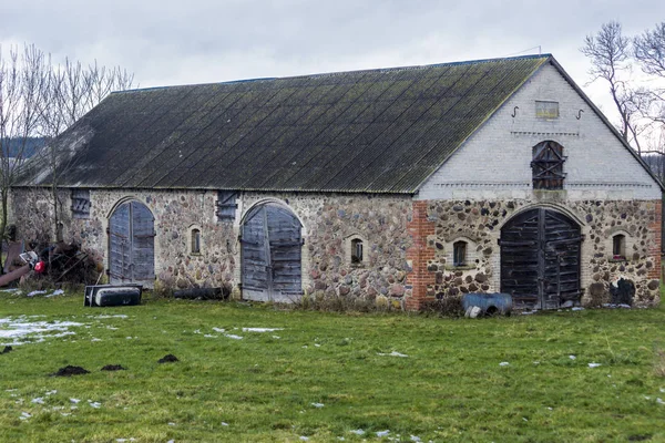 緑の牧草地の雪のビット 放棄された酪農場の石造りの納屋を放棄しました ヨーロッパの冬の始まり — ストック写真