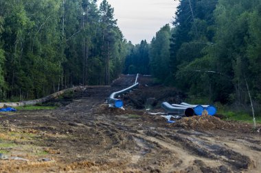 Gaz boru hattının yeniden inşası. Eski paslı boruları yenileriyle değiştirmek. Arka plan olarak Taiga. Kazılmış toprak ve inşaat ekipmanlarının izleri.