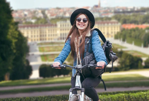 Güzel Avrupa kız bir şehir arka plan üzerinde bir bisiklet sürme