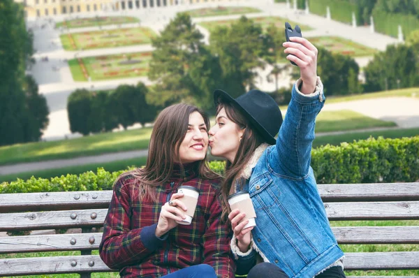 Güzel Avrupa kızlar kahve içmek ve zemin şehrin karşı bankta selfie olun