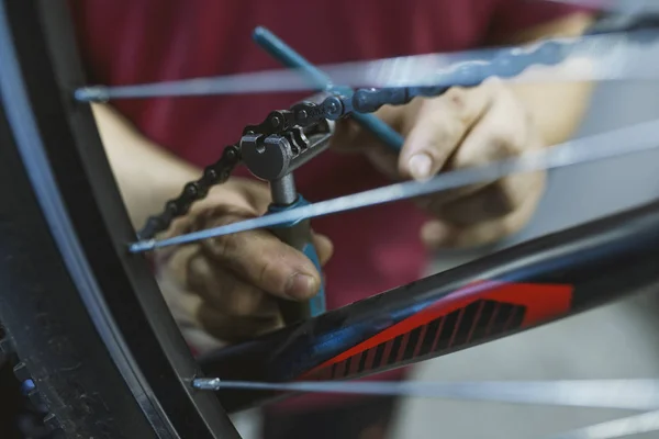 Mechanic in a bicycle repair shop fixing the chain of a bike. Mechanic repairing bicycle transmission. Bicycle Repair Shop and Working Man. Assembly of the derailleur in the bike