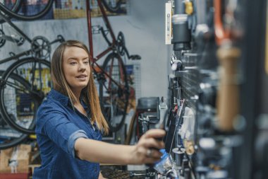 İşyerinde kadın makinist. Bir çalışan için doğru aracı arama portresi. Bisiklet tamircisi ve dükkanı aletlerini. Beyaz makinist doğru aracı seçme.